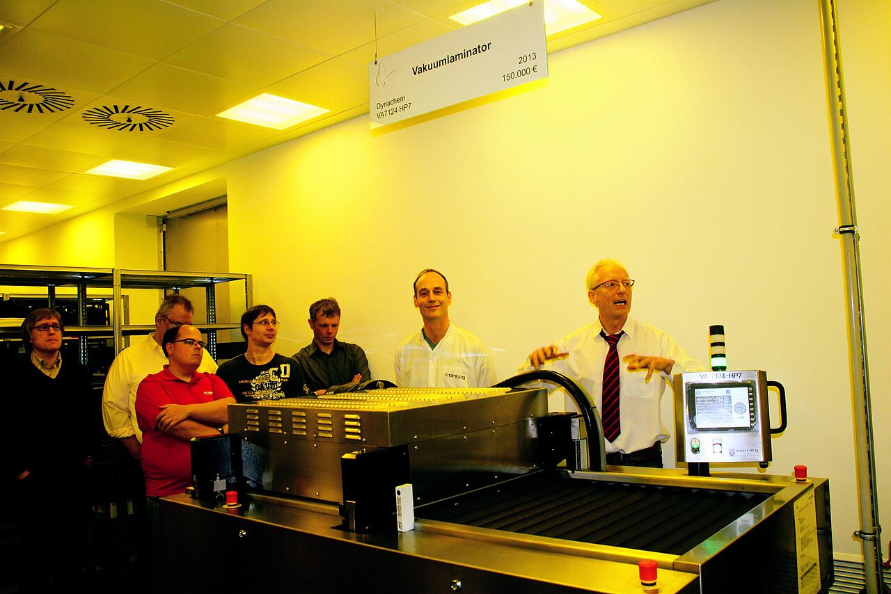 Interne Weiterbildung bei CONTAG: Eine Gruppe von Mitarbeitern verfolgt konzentriert eine technische Einweisung durch einen Experten an einer spezialisierten Produktionsanlage.