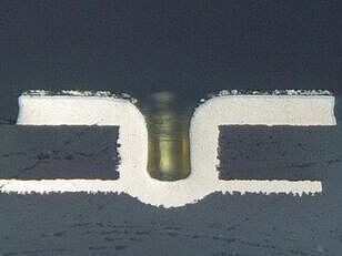 Mikroskopisches Schliffbild eines mechanisch gebohrten Microvias, das die charakteristische V-Form der Bohrspitze zeigt.