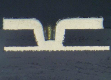 Mikroskopisches Schliffbild eines lasergebohrten Microvias mit präzisen, steilen Wandungen und sauberer Anbindung an die Ziel-Lage.